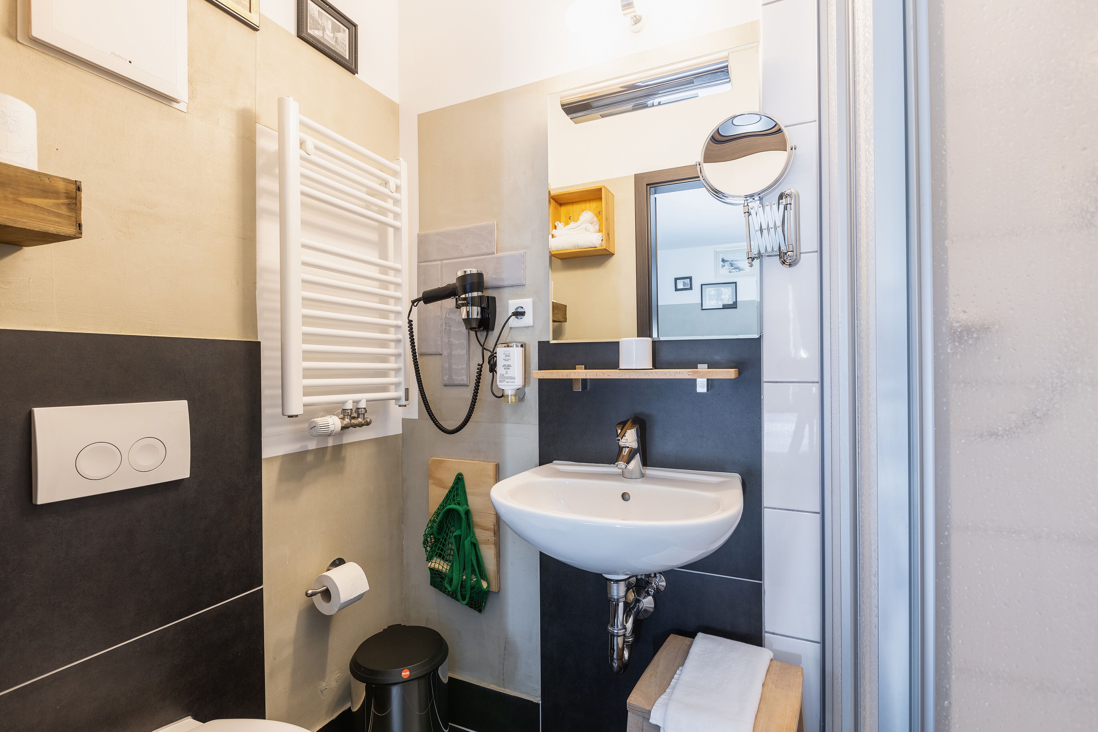 A modern bathroom with a white sink, a towel rack, a mirror, and a towel hanging on the wall.