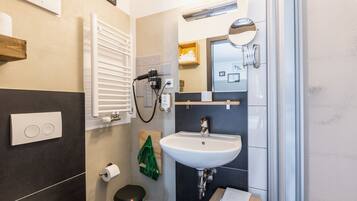 A modern bathroom with a white sink, a towel rack, a mirror, and a towel hanging on the wall.