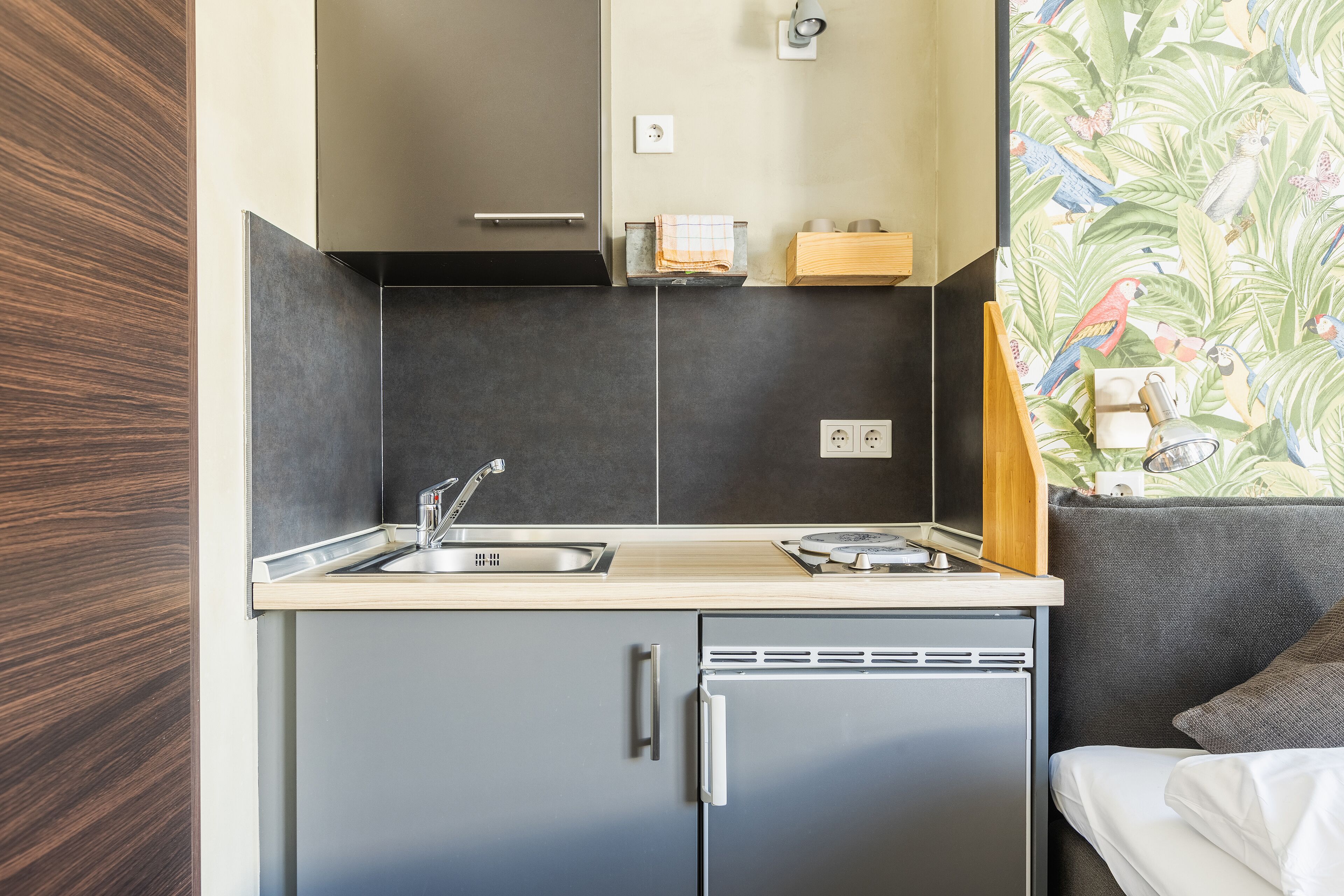 A compact kitchenette with a sink, a small refrigerator, and a wooden countertop.