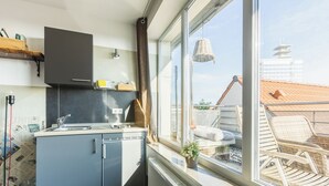 A modern kitchen with a large window, a built-in oven, and a view of the city. - aappartel boardinghouse city center (Bielefeld)