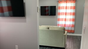 Een kamer met een bed, een televisie, een bank en een raam met gordijnen.