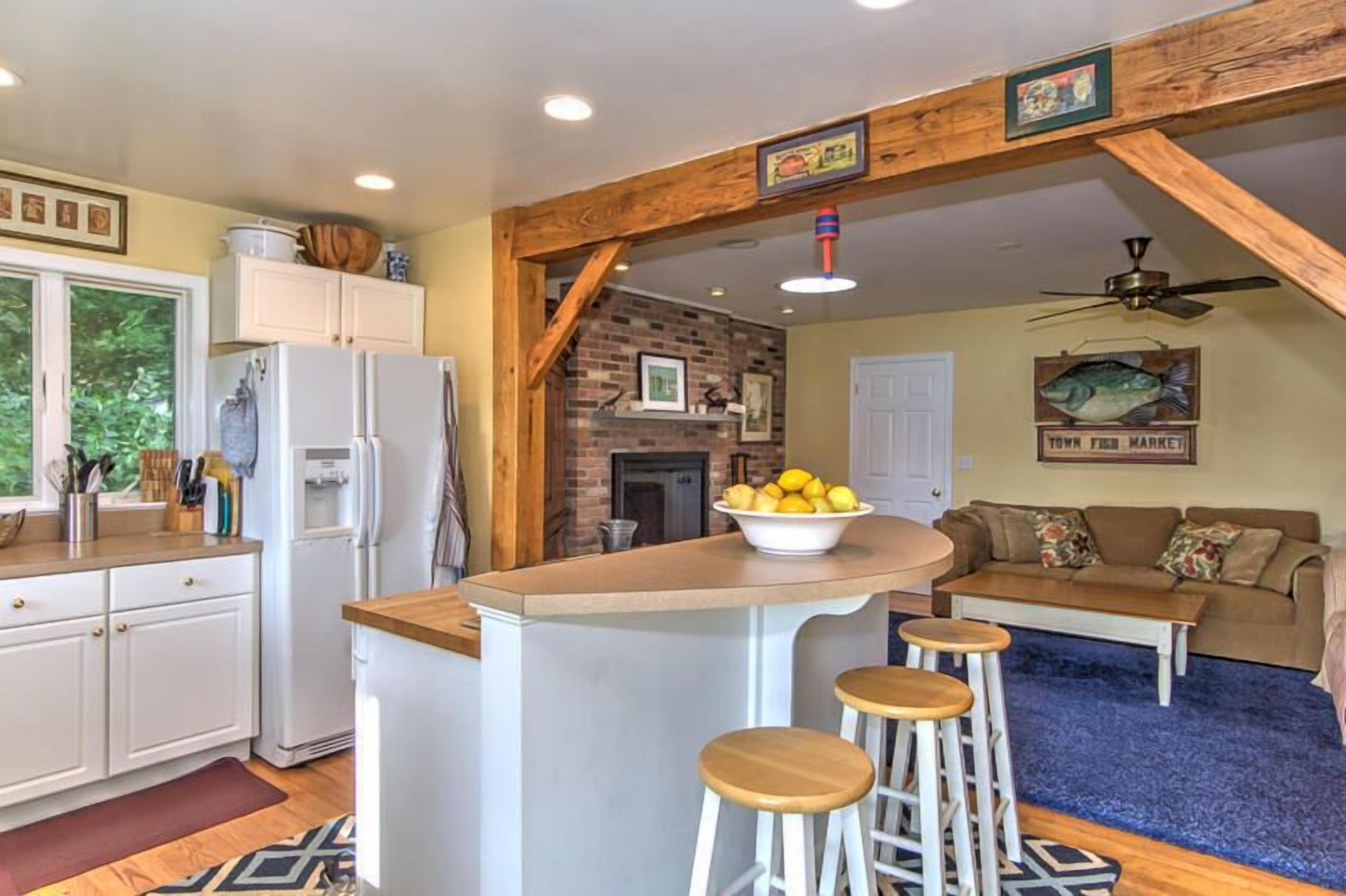 A kitchen with a central island, bar stools, a refrigerator, and a fish-themed wall decoration.