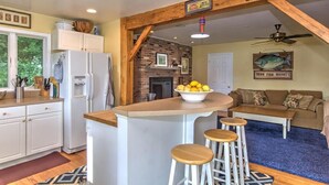 Een keuken met een centraal eiland, barstoelen, een koelkast en een wanddecoratie met vismotieven.