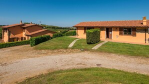Una casa de dues plantes amb teulada de rajola, carrec de grava i un jardí ben cuidat.