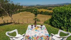 Taula a l'aire lliure amb vista a turons suaus i un cel serè.