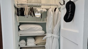 A narrow walk-in closet with white shelves, a hanging robe, and a wicker basket. - Luxurious and Relaxing Elegance Upstairs 🚭 (St. Augustine)