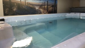 Une piscine avec vue sur le coucher de soleil, un jacuzzi et une terrasse en bois.