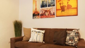 A brown sofa with patterned cushions and a tall green plant beside it. - Bnbook- Via Torino Train Station (Rho)