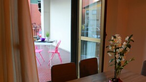 A room with a wooden table, a potted plant, and a view of a balcony with chairs and a small table. - Bnbook- Via Torino Train Station (Rho)