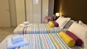 A hotel room with two beds, striped bedding, a chair, and a lamp. - Bnbook- Via Torino Train Station (Rho)