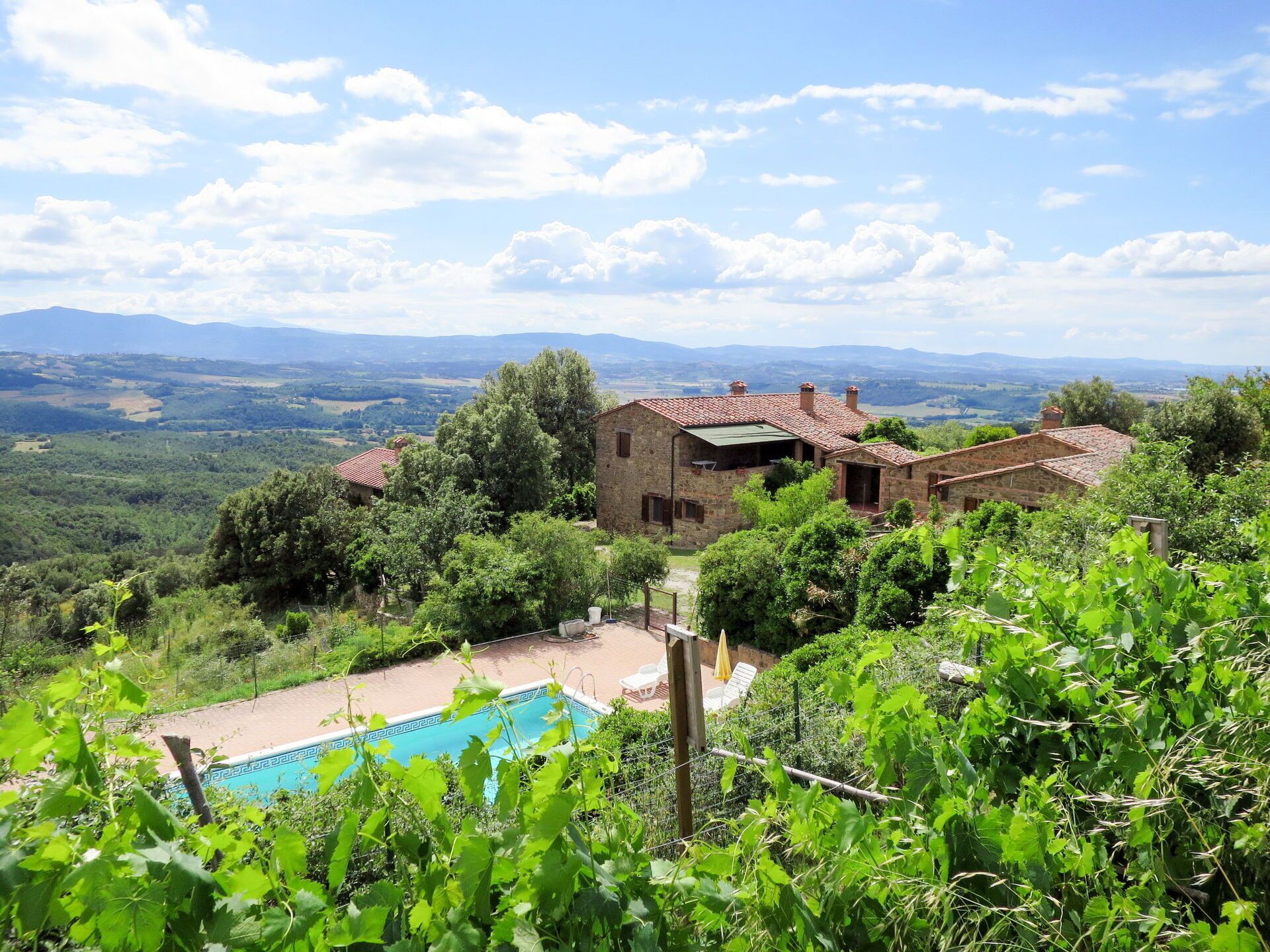 Une maison en pierre dotée d’une piscine, entourée d’une végétation luxuriante et avec des montagnes en toile de fond.