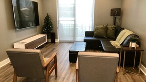 Un salon avec un téléviseur à écran plat, un sapin de Noël, un canapé et une table basse.
