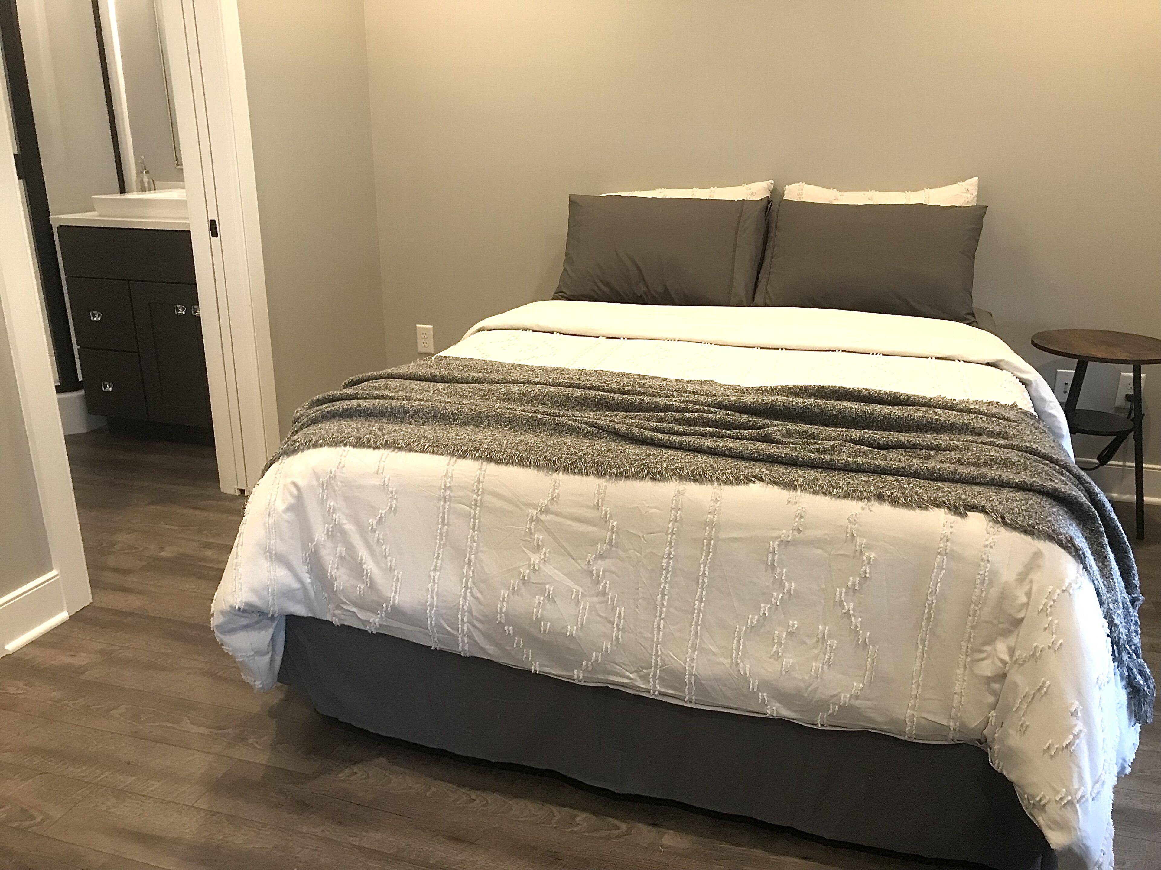 Een slaapkamer met een bed, een nachtkastje en een stoel.