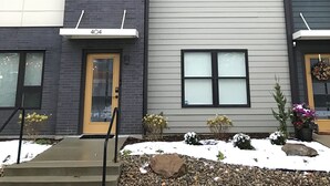 Un immeuble résidentiel à plusieurs étages, doté d’une architecture moderne, avec un balcon au deuxième étage et une entrée principale avec une porte.