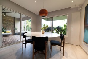 A modern dining area with a round table, four chairs, and a pendant light. - Eagle Vacation Home (Oranjestad)