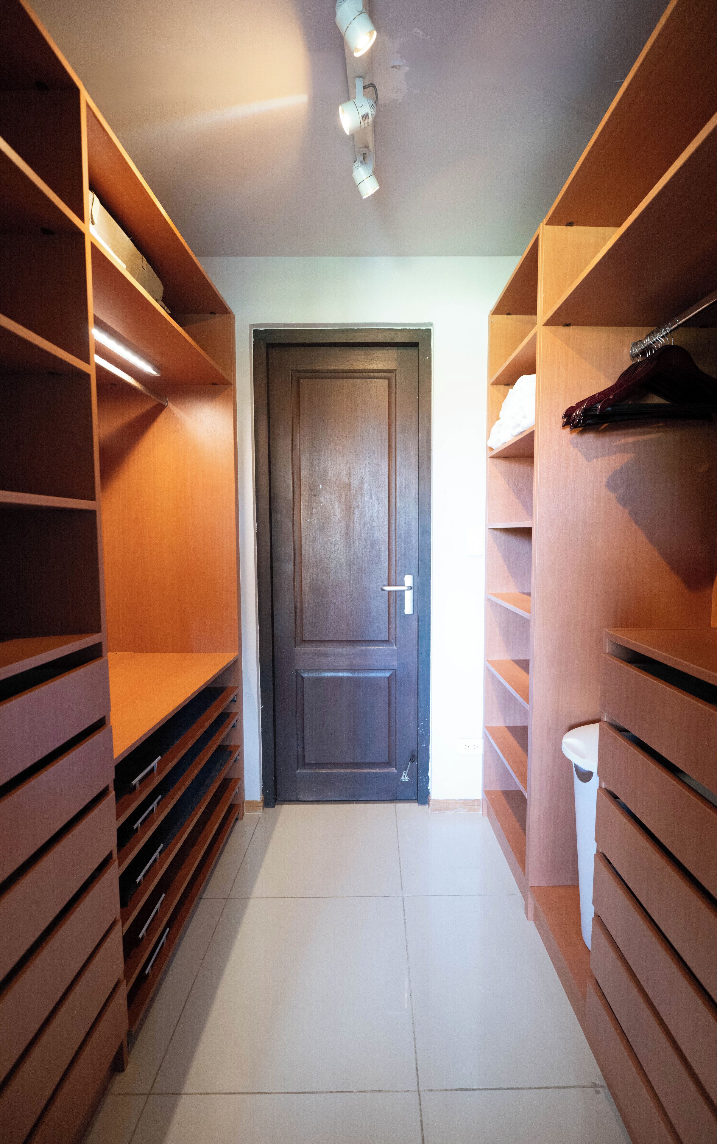Un dressing avec des étagères en bois, une porte et une poubelle.
