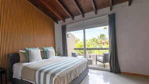 A modern hotel room with a large bed, a wooden slatted wall, a balcony with a view of palm trees, and a tiled floor.