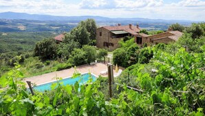 A stone house with a swimming pool surrounded by lush greenery and mountains in the background. - Nice apartment in villa for 6 guests with WIFI, pool, TV, terrace and pets allowed (Paciano)