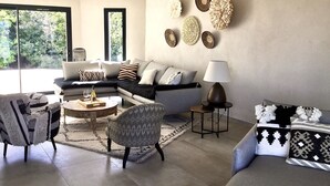 Un salon moderne comprenant un canapé, des fauteuils, une table basse et des œuvres d’art décoratives murales.