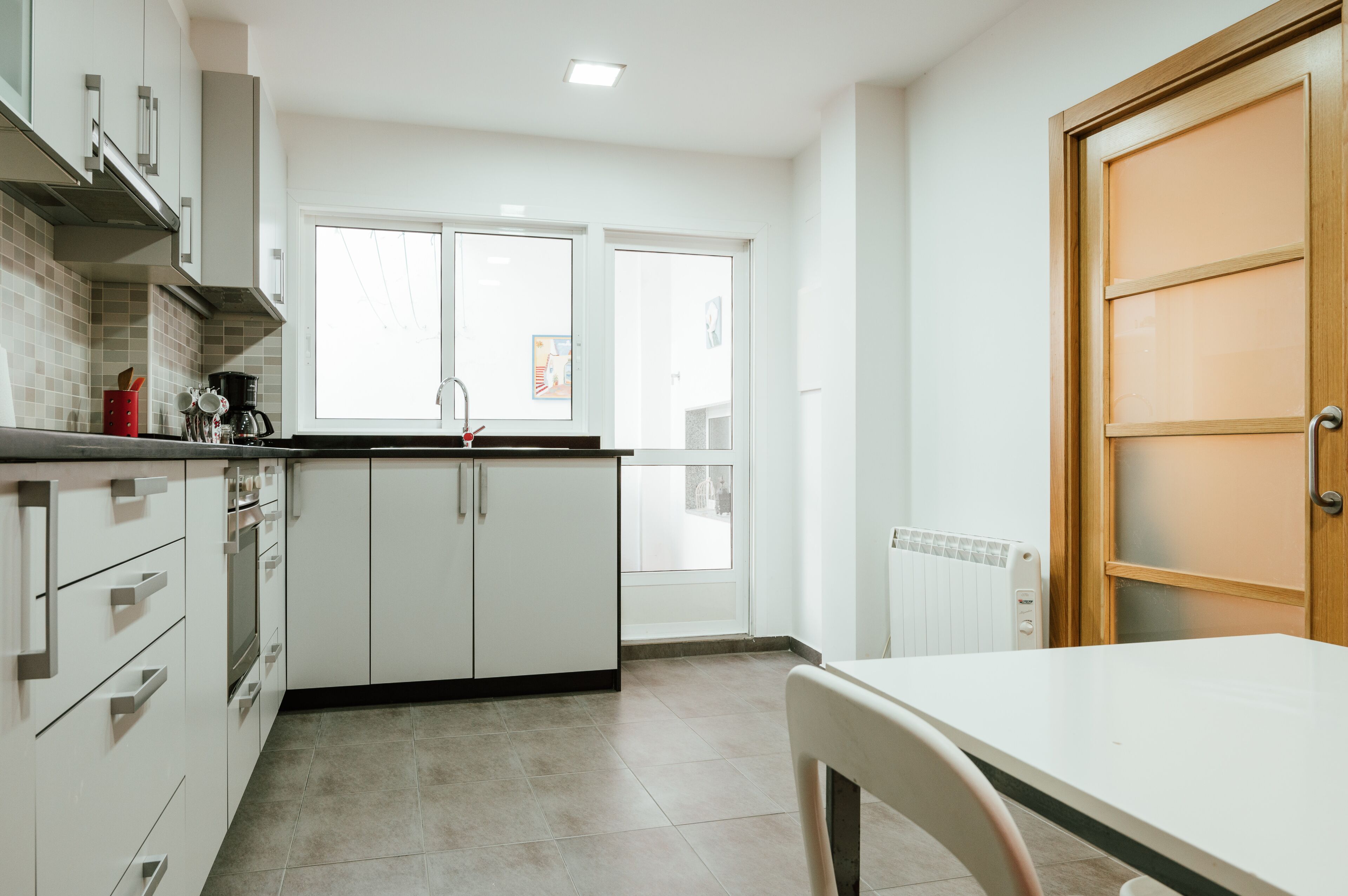 A modern kitchen with white cabinets, a black countertop, and a window with a view.