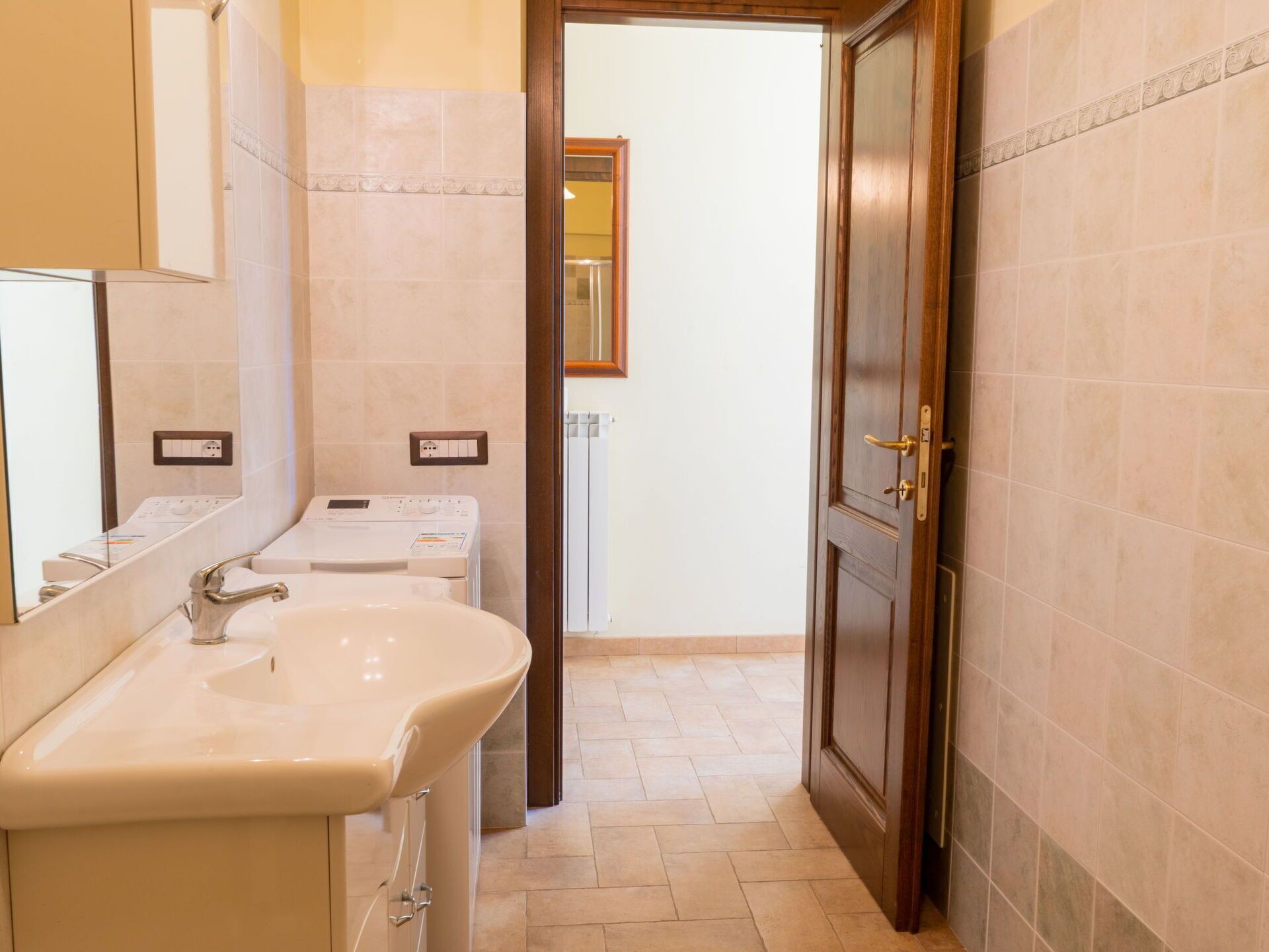 Ein Badezimmer mit Waschbecken, Spiegel und einer Tür zu einem anderen Raum.