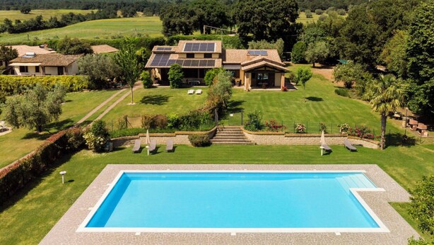 A residential property with a swimming pool, solar panels, and a well-maintained lawn. - Lovely apartment in villa for 6 guests with WIFI, pool, TV and terrace (Lake Bolsena)
