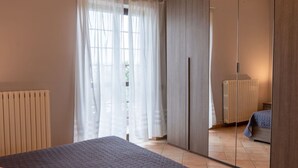 A bedroom with a bed, a wardrobe, a radiator, and a window with curtains. - Lovely apartment in villa for 6 guests with WIFI, pool, TV and terrace (Lake Bolsena)