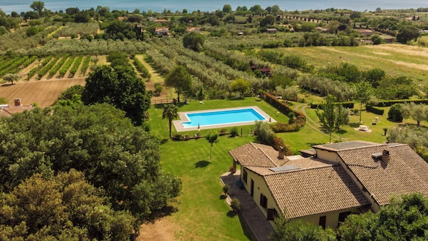 Una villa con piscina, rodeada de exuberante vegetación y vistas a un lago.