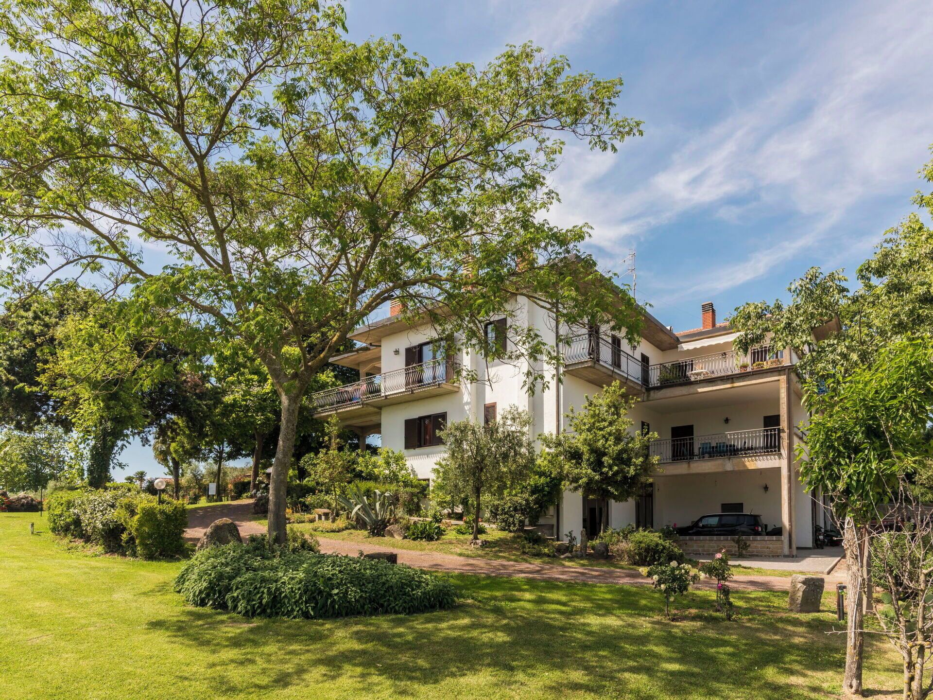 Ein zweistöckiges Haus mit Garten, ein geparktes Auto davor und ein klarer Himmel.