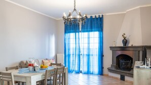 Un comedor con una mesa dispuesta para cuatro personas, una chimenea y una cortina azul.