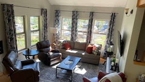 A living room with a sofa, two armchairs, a coffee table, and a TV. - Spacious 3-Story Home, 4 bedrooms, Sleeps 12, Easy Trailer Parking (Detroit)