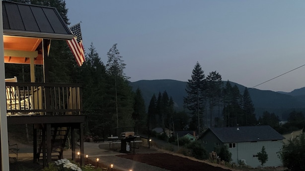A building with a deck, an American flag, and a gravel path with lights. - Spacious 3-Story Home, 4 bedrooms, Sleeps 12, Easy Trailer Parking (Detroit)