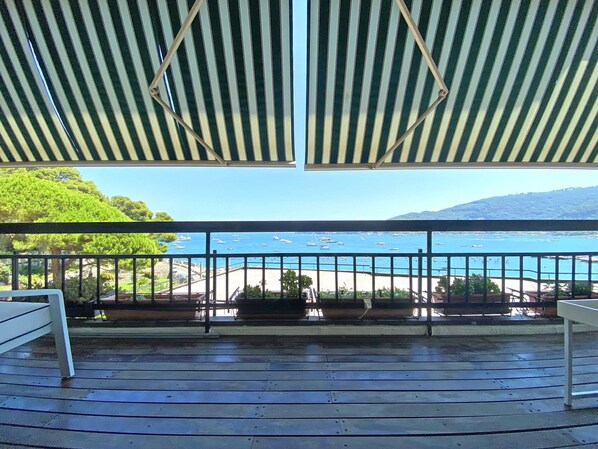 A covered outdoor area with a view of the sea and a beach.
