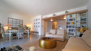Una sala de estar con sofá, mesa de centro y estantería. Hay un comedor con sillas y una mesa.