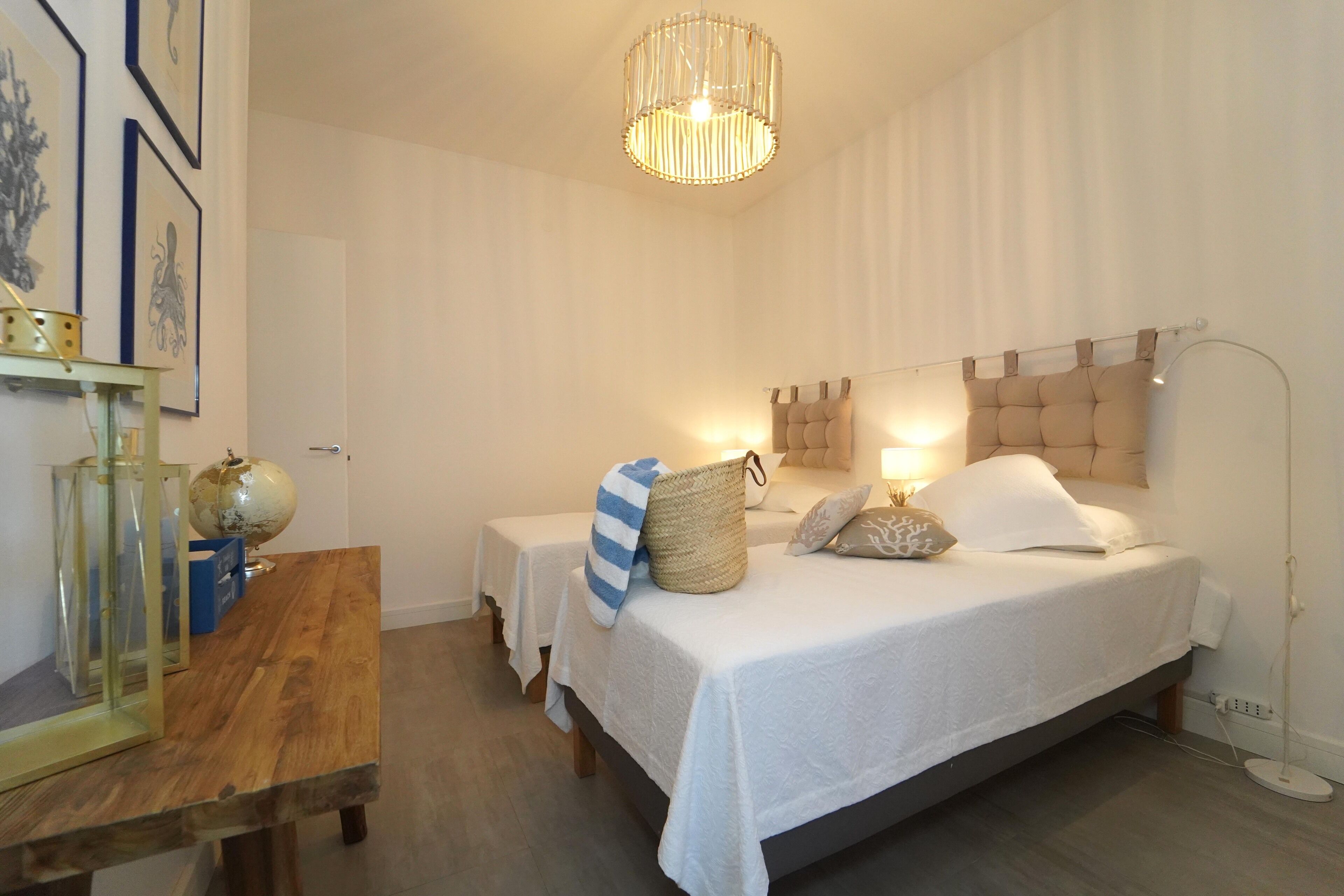 Un dormitorio con cama, mesitas de noche, lámpara y un globo terráqueo sobre una mesa.