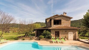 A stone villa with a swimming pool and lounge chairs.