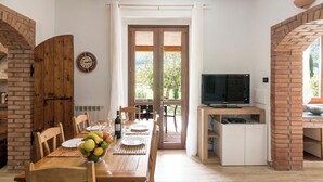A dining area with a wooden table set for four, a television, and a brick fireplace.