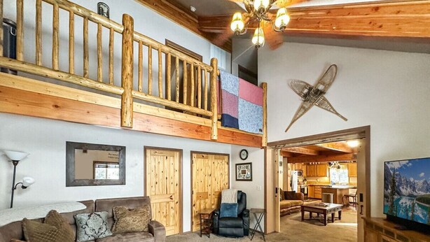 A spacious living area with a wooden staircase, a sofa set, a coffee table, and a kitchen in the background.