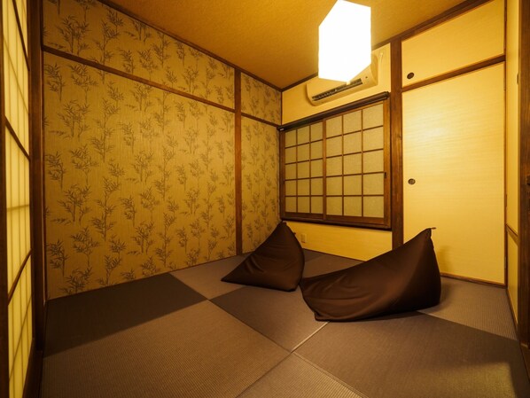 A traditional Japanese room with tatami flooring, shoji screens, and a futon bed.