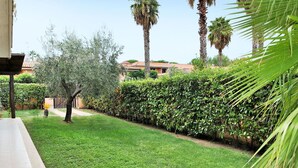 Un jardin bien entretenu, avec une variété d’arbres et une haie soigneusement taillée.