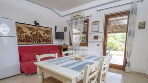 Un coin repas avec une table dressée pour quatre personnes, un canapé rouge, un téléviseur et un élément décoratif mural.