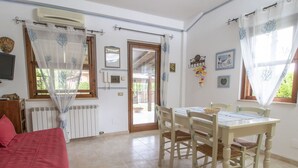 Une pièce comprenant un lit, une table à manger avec des chaises, un radiateur et une fenêtre avec des rideaux.