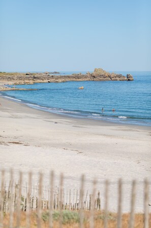 A beach with clear blue water, rocky formations in the distance, and a sandy shore. - Country Side by the sea. The countryside by the sea in a contemporary house. (Loctudy)