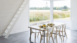 Un comedor amplio con techo alto, una escalera y un gran ventanal con vistas a un campo.