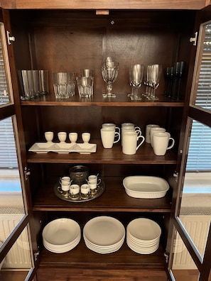 Storage cabinet with ample space for tableware, featuring multiple shelves and a simple design.