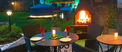 An outdoor patio with tables and chairs, a fire feature, and a covered seating area.