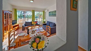 Un soggiorno spazioso con zona pranzo, divano, televisione e un quadro appeso al muro.