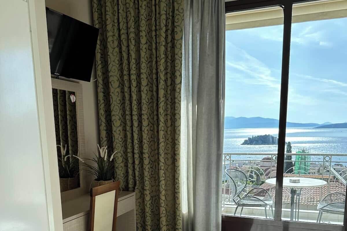 Habitación de hotel con cama, escritorio, silla, televisor y vista al mar.