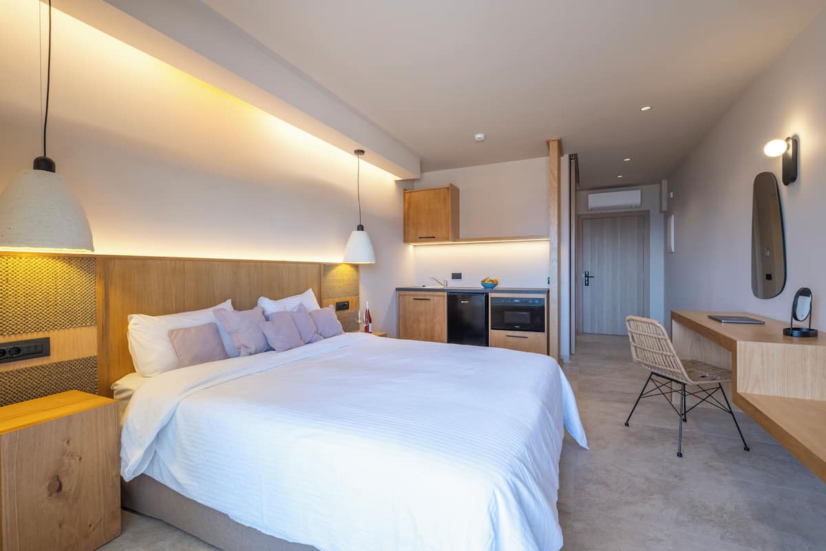 Una habitación de hotel moderna con una cama grande, un escritorio, una silla y una kitchenette.