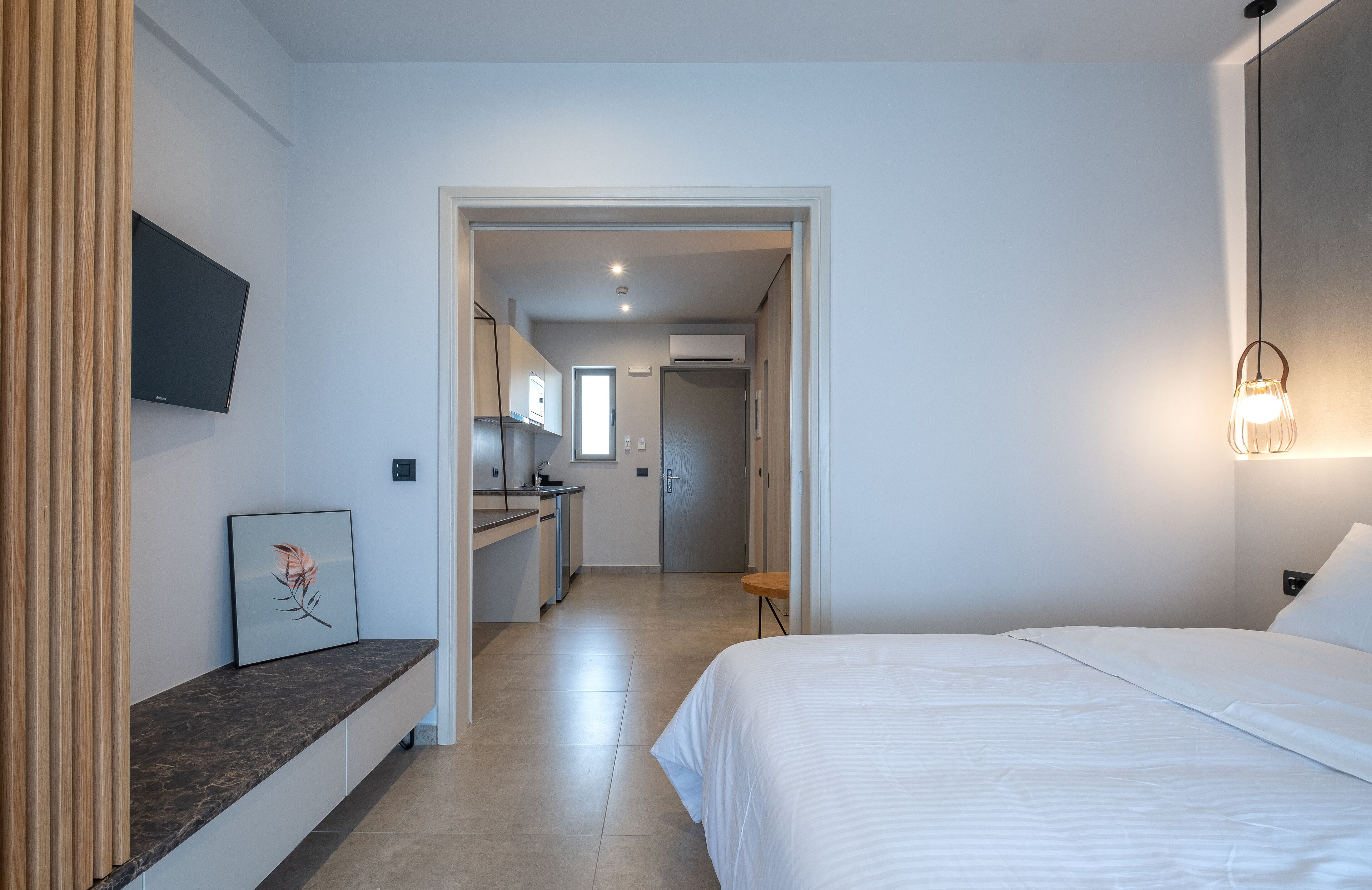 Una habitación de hotel moderna con cama, escritorio y kitchenette.